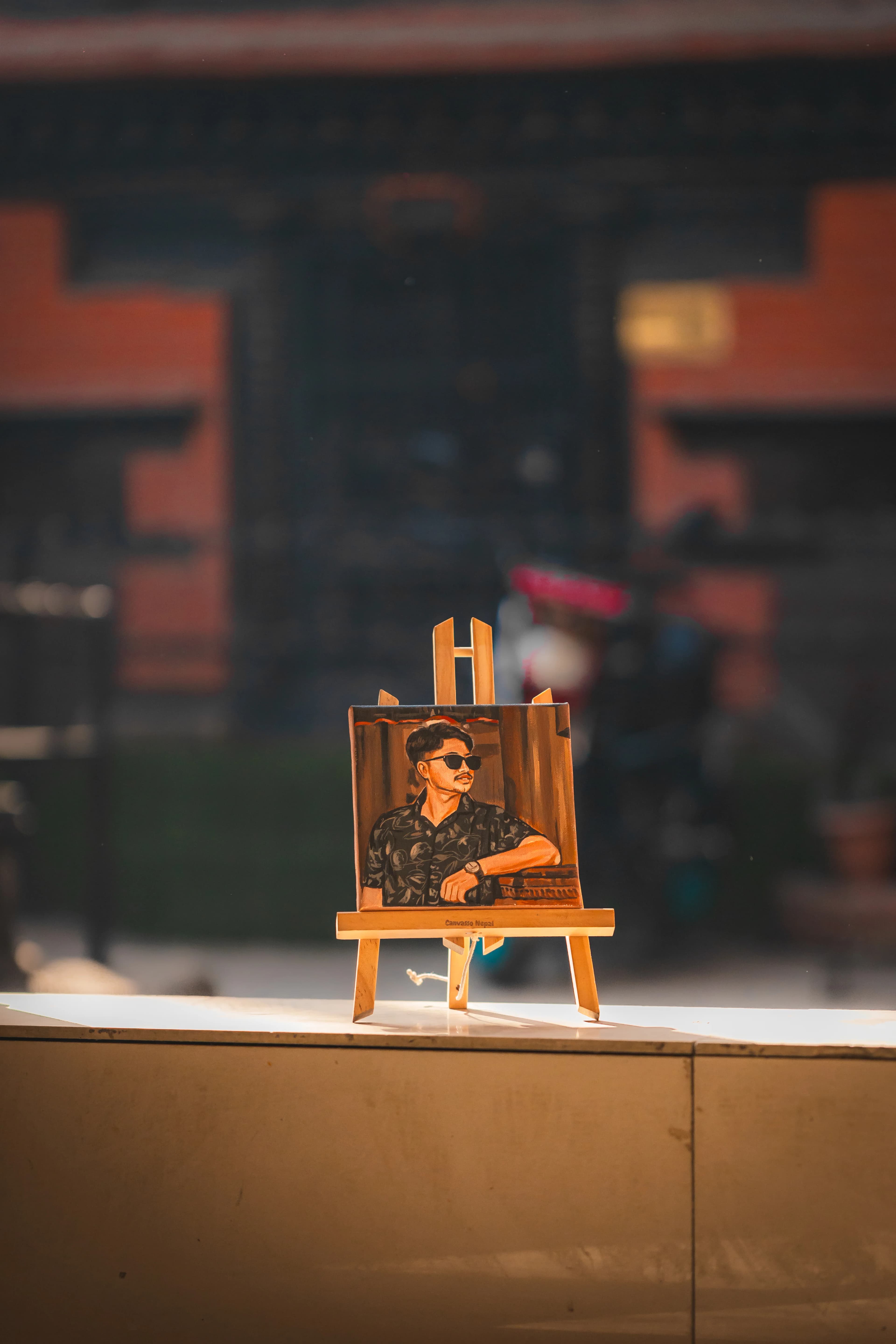 Mini canvas portrait of a smiling person on a small easel in warm studio light